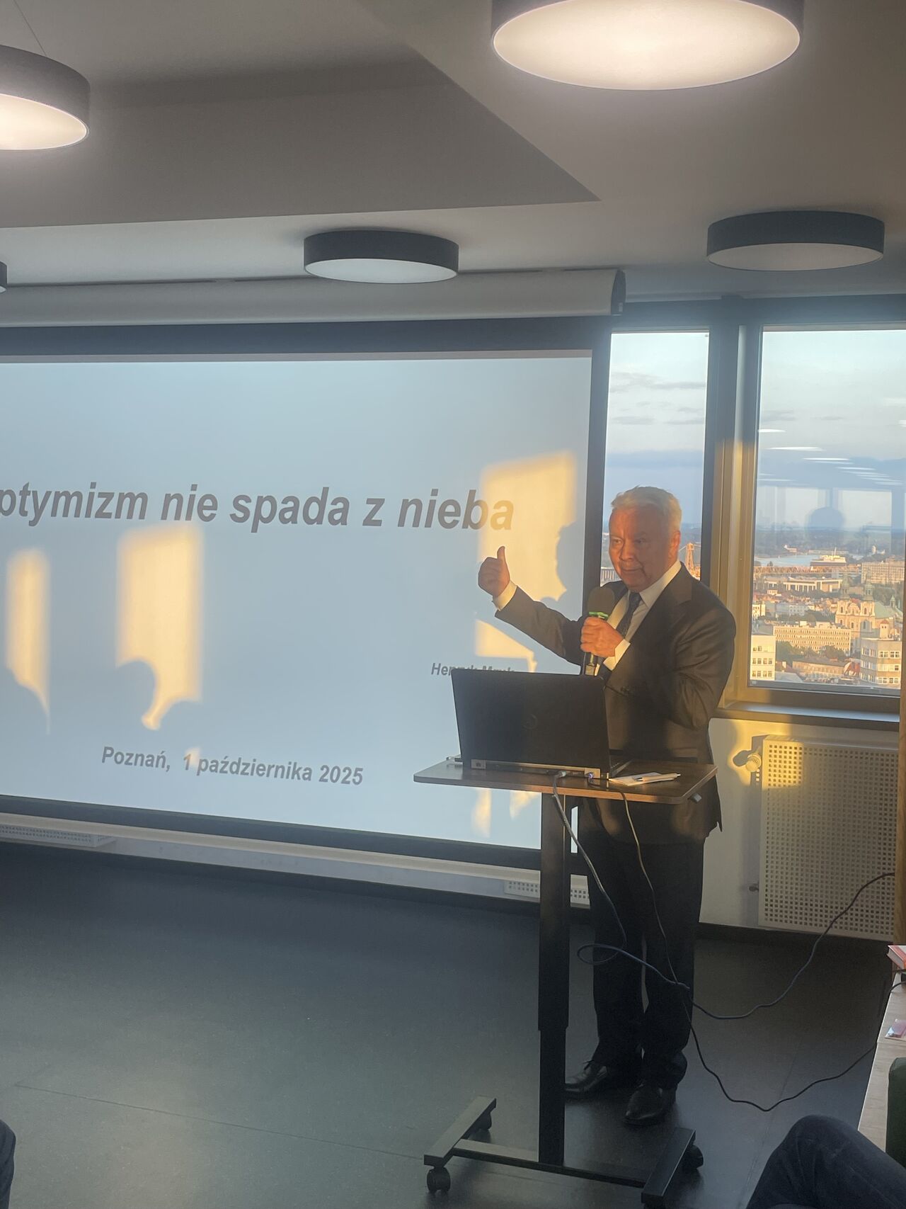 A man in a suit stands at the lectern and gives a presentation